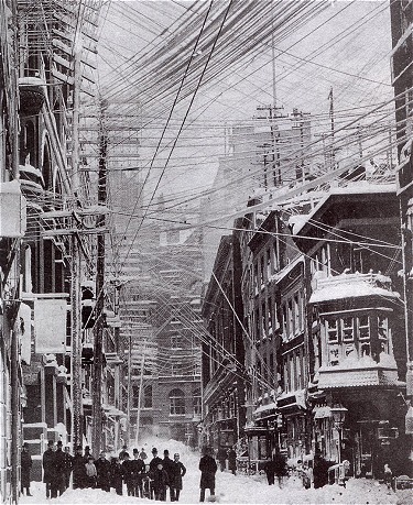 Figure 1 - New York City during the Great Blizzard of 1888, showing the tangle of electrical wires taking the strain of the snow.  After the disaster of the storm New York City began the task of placing electrical utilities below ground.  From the Wikicommons and in the public domain.